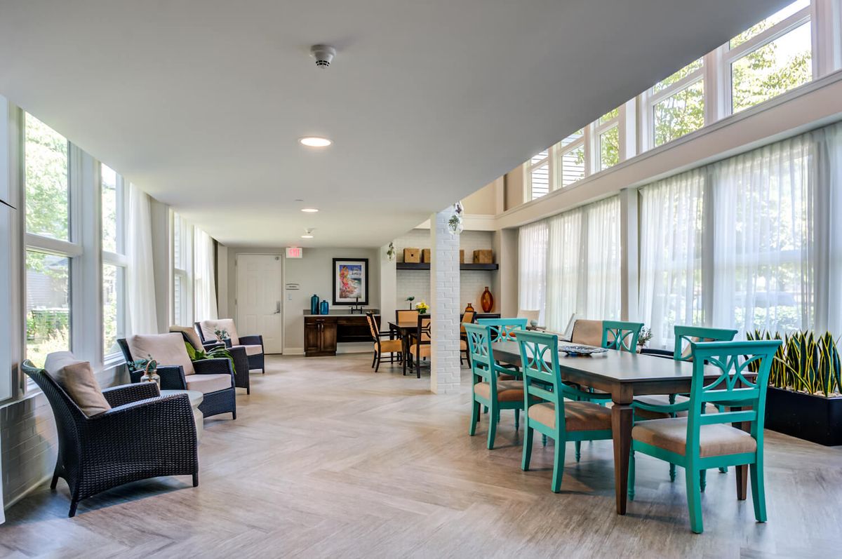 A bright and spacious living and dining area with colorful chairs and large windows.