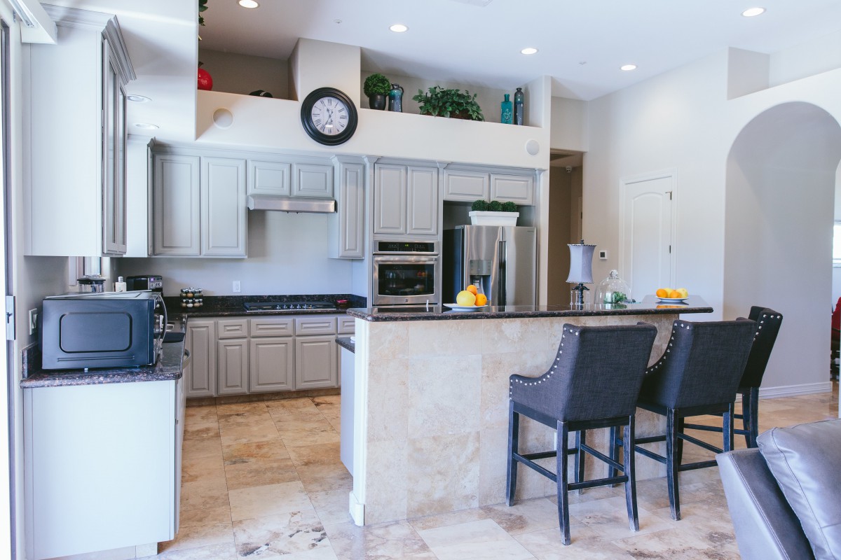 A modern kitchen interior featuring sleek cabinetry, a central island with bar stools, and stainless steel appliances.
