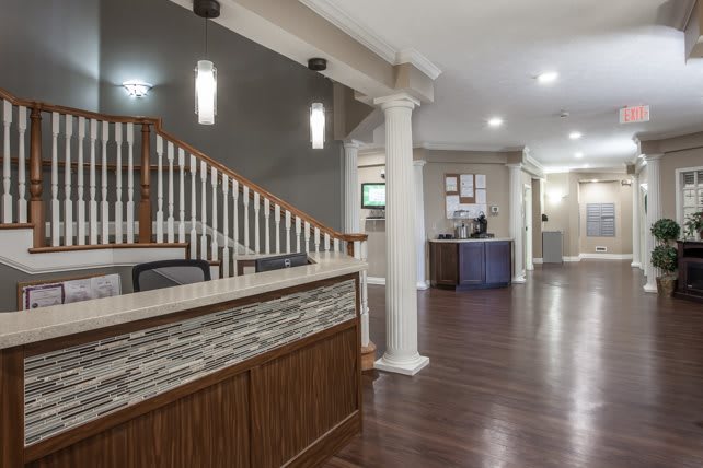A sleek and modern reception area with wood flooring, stylish lighting, and a prominent staircase.