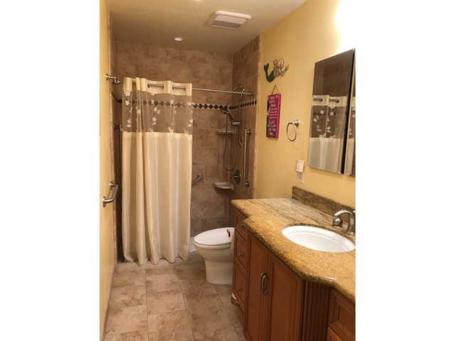A neatly arranged bathroom with a shower curtain, toilet, and sink on a tiled floor.