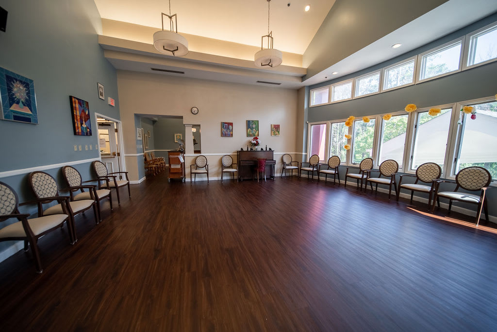 Spacious room with hardwood floors and chairs arranged along the walls, featuring large windows and decorative artwork.