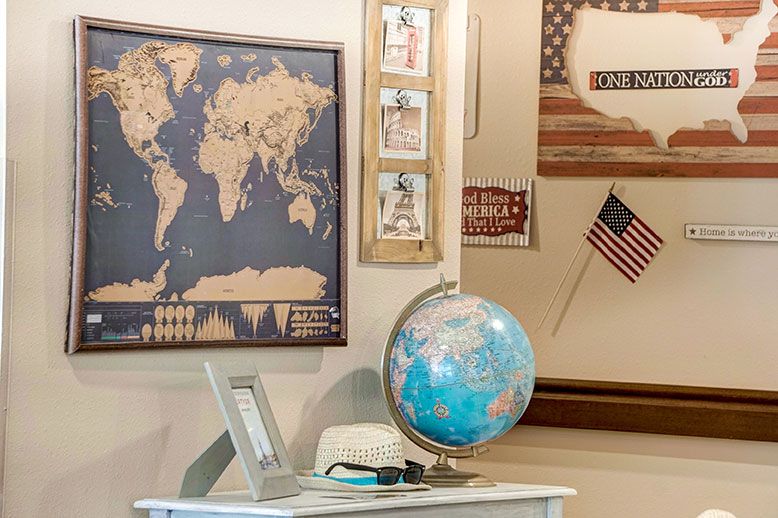 A room decorated with a world map, a globe on a table, and an American flag on the wall.