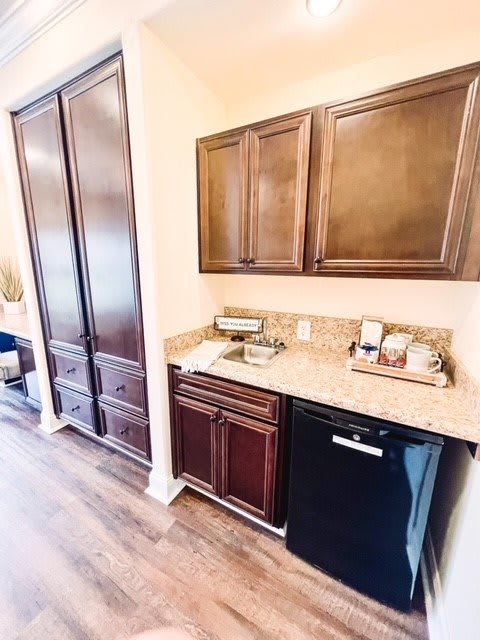 A compact kitchenette with wooden cabinets, a mini fridge, and a clean countertop.