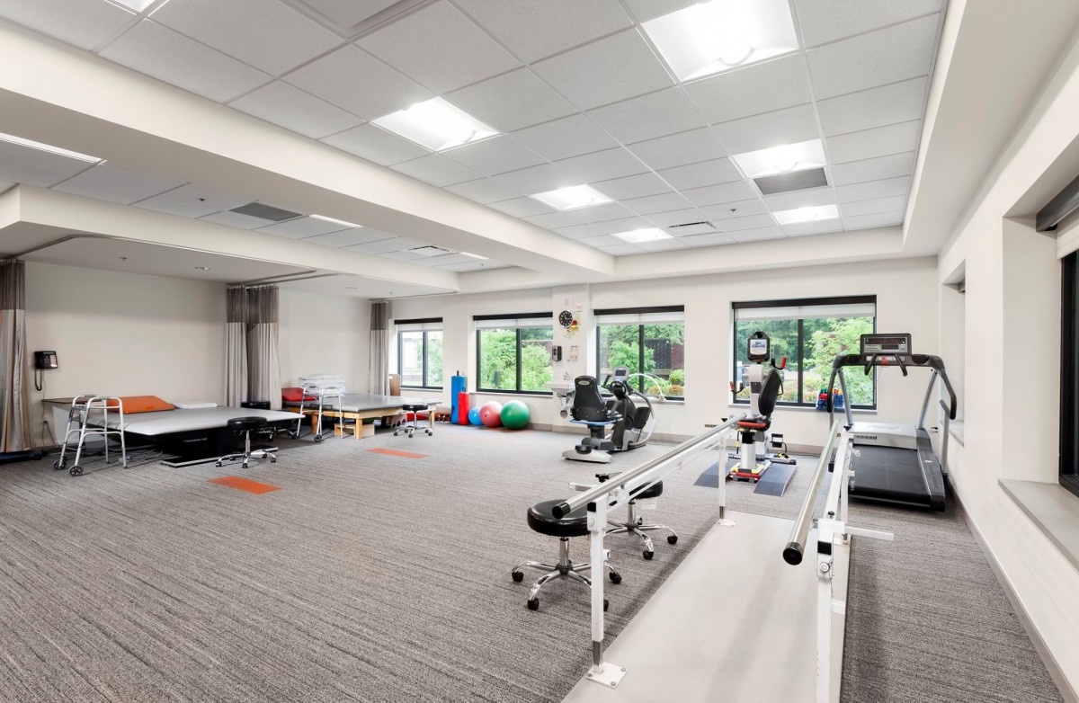 A spacious gym or physical therapy room equipped with exercise equipment and rehabilitation tools.