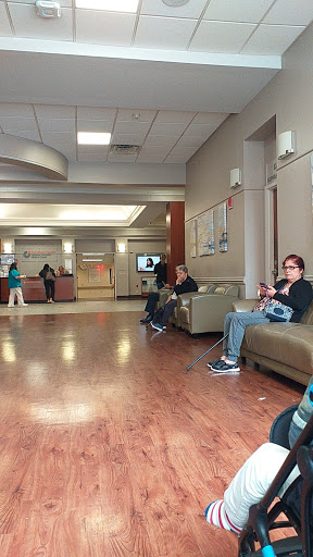 A calm waiting area in a hospital with people seated and others in the background.