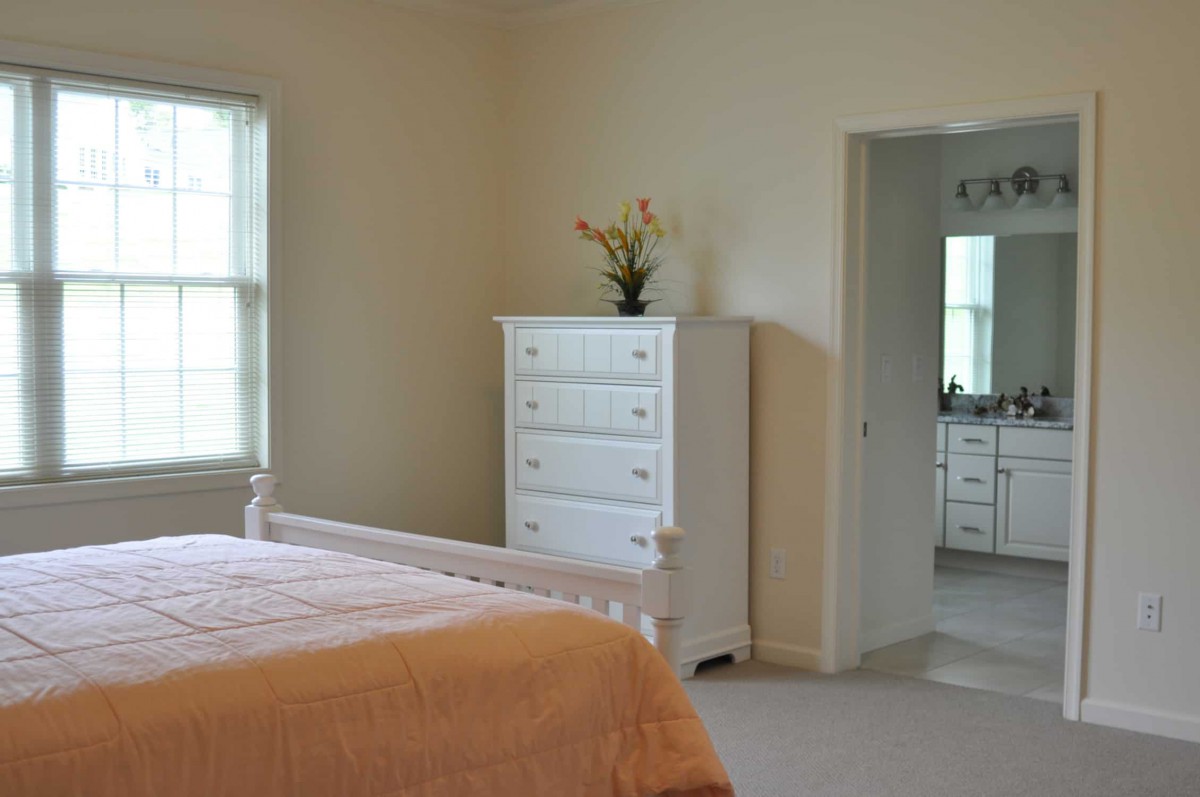 A minimalist bedroom with a bed and white dresser.