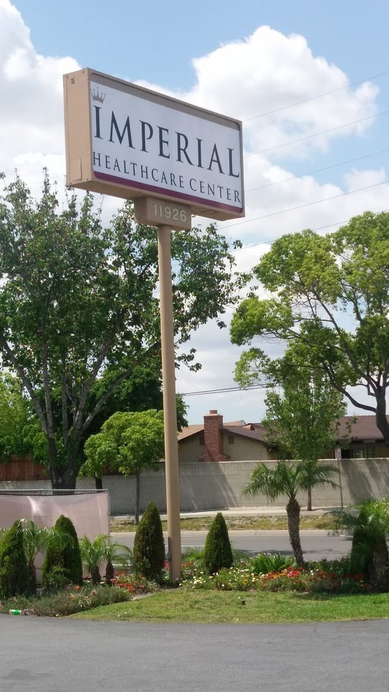A sign for a healthcare center displayed outdoors with trees and buildings in the background.