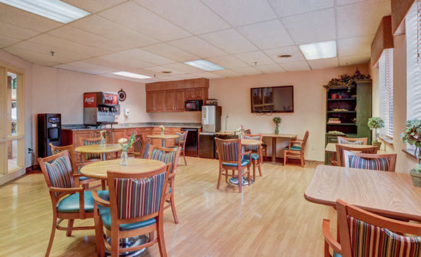 An inviting dining area with several round tables and chairs, adjacent to a kitchenette.