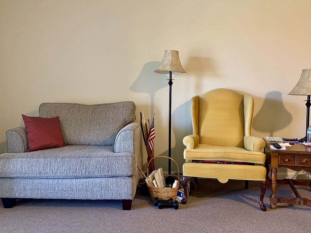 A cozy living room corner with a sofa, armchair, and floor lamp.