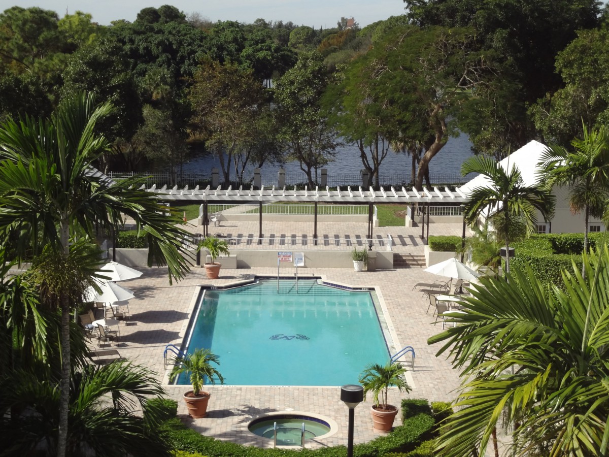 A scenic view of an outdoor pool area surrounded by lush greenery and a serene lake in the background.