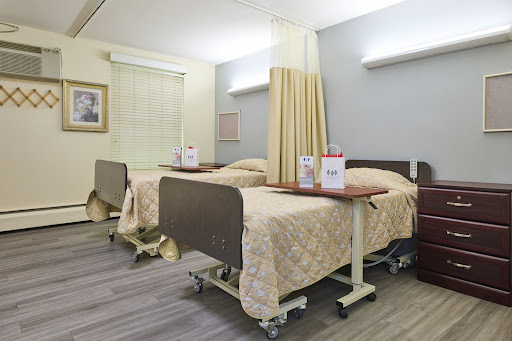 A view of a hospital patient room featuring two beds and privacy curtains.