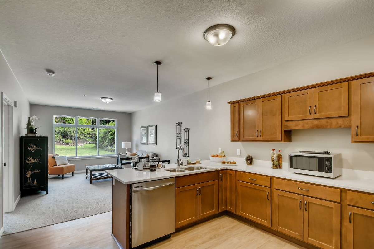 A modern open-concept kitchen with wooden cabinets and stainless steel appliances.