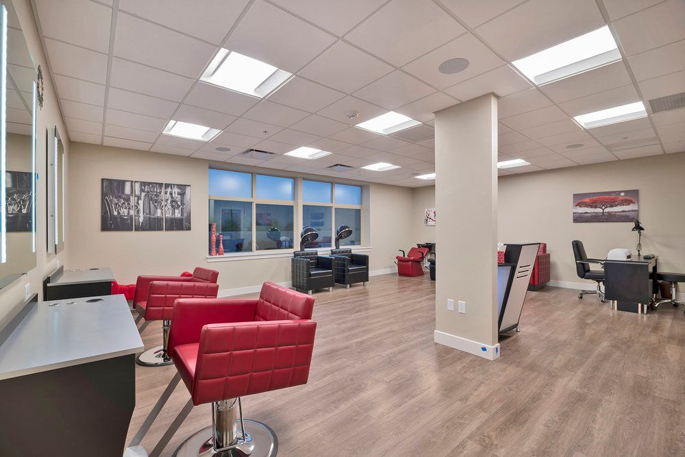 A modern hair salon interior with red chairs and bright lighting.