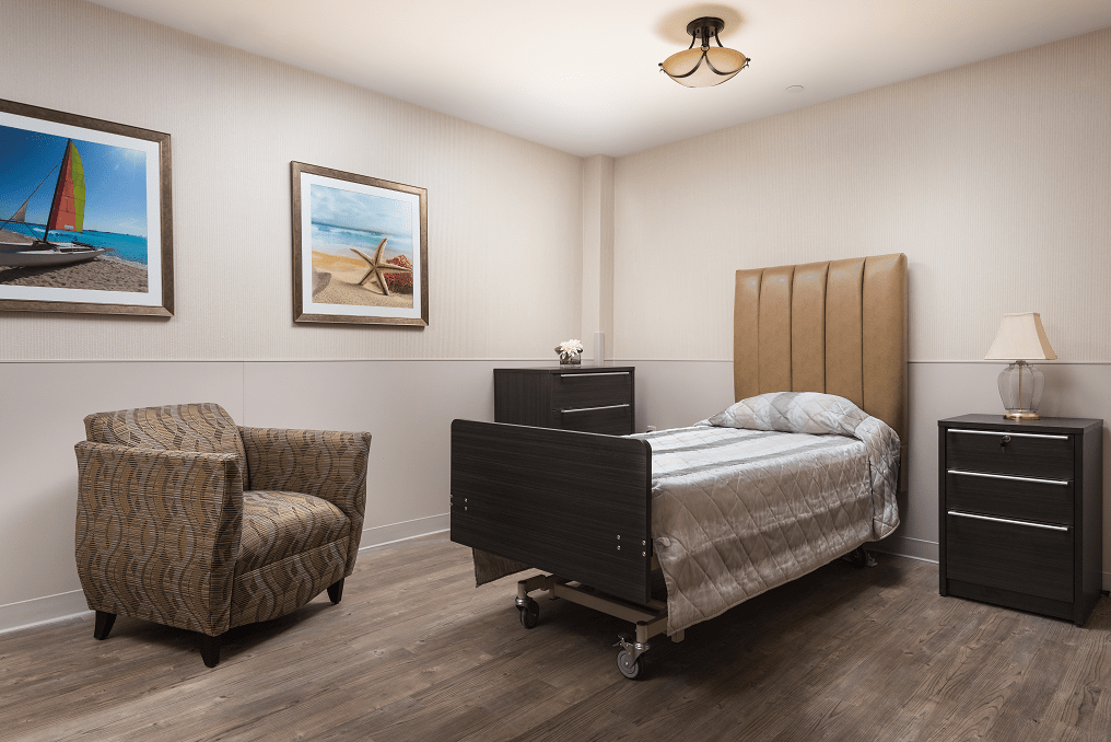 A minimalist bedroom with a single bed, armchair, and wall painting.