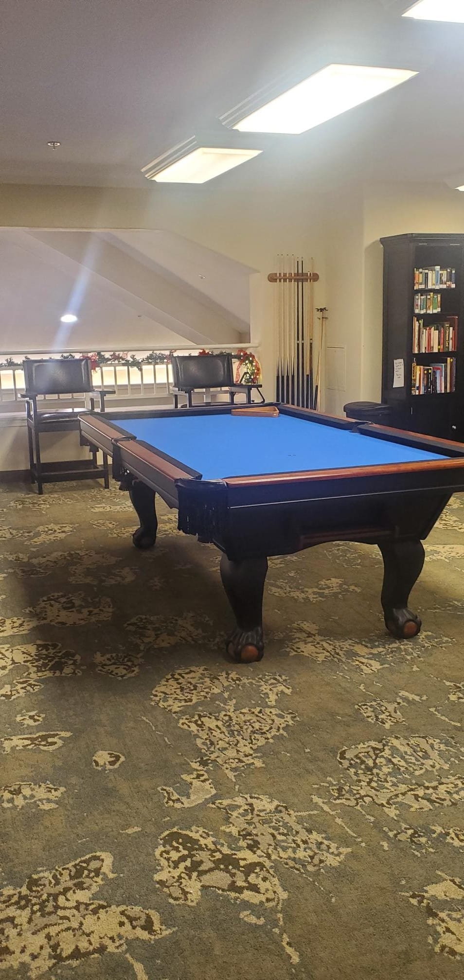 A pool table with a blue felt surface in a cozy game room setting.