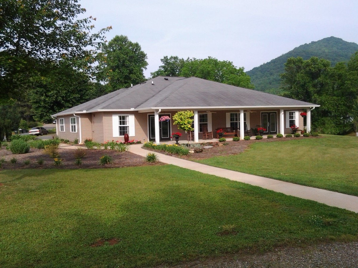A single-story house with a well-maintained lawn and surrounding trees.