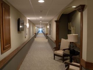 A long, well-lit hallway with chairs and lamps positioned along the sides.