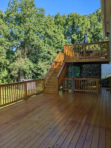 A spacious wooden deck surrounded by lush greenery.