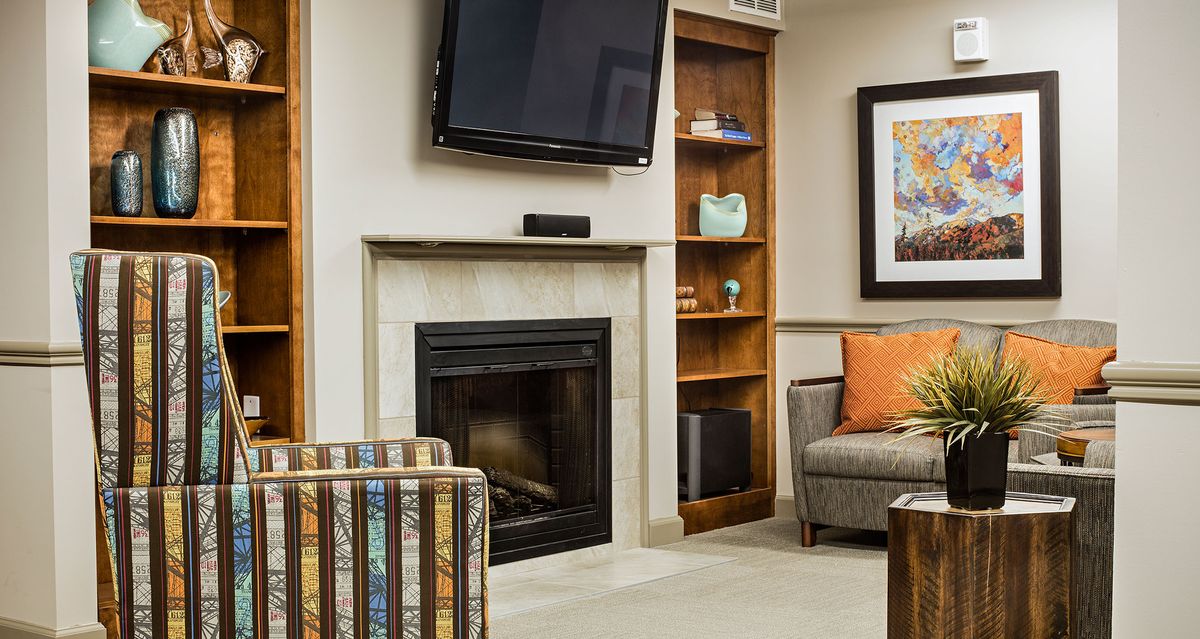 A cozy living room with a fireplace, television, bookshelf, and comfortable seating.