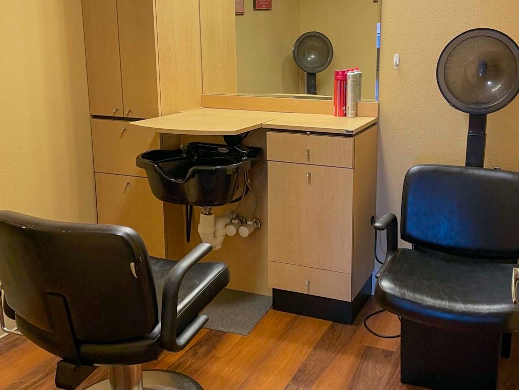 An interior view of a hair salon with styling chairs, a washing sink, and mirrors.