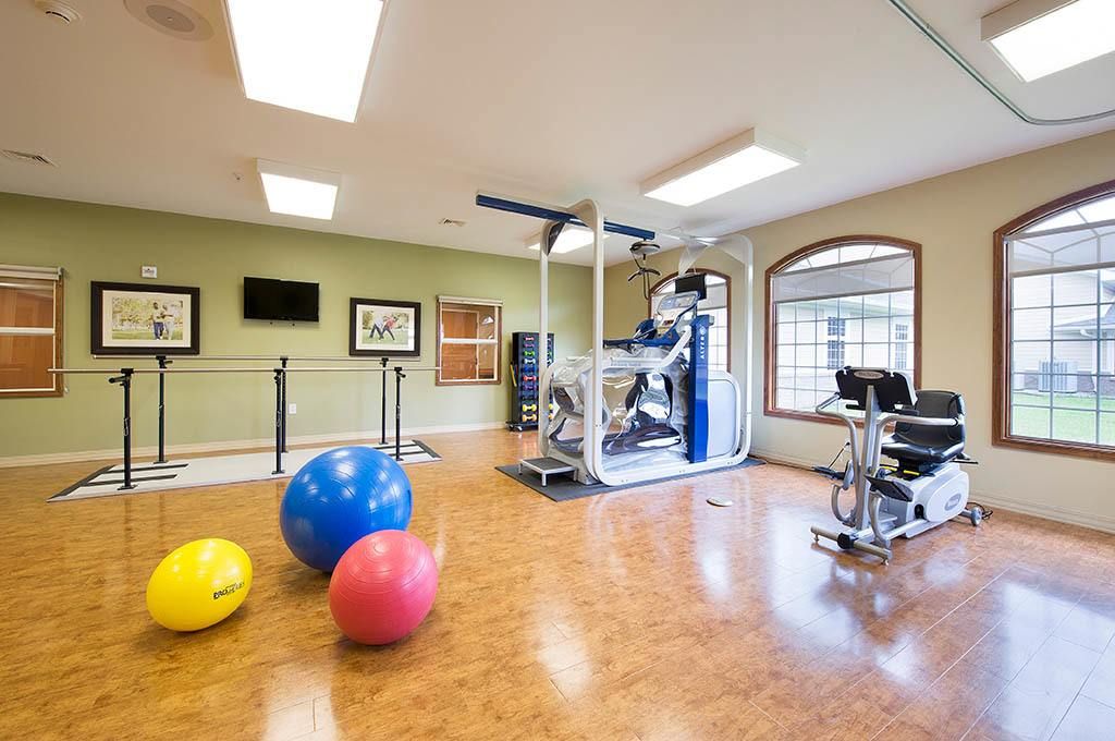 A well-equipped gym with exercise balls, a treadmill, and other workout machines.