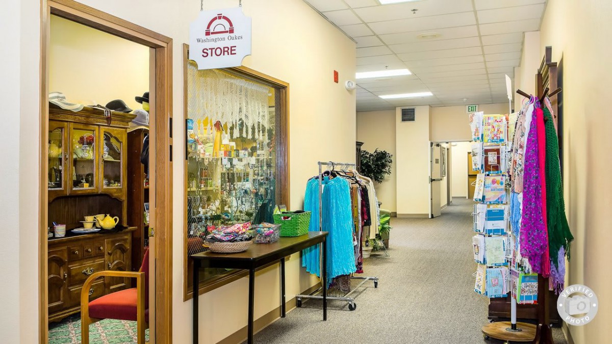 A cozy indoor hallway with a small storefront displaying clothing items on racks and tables.
