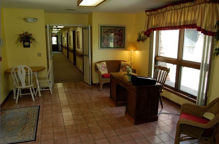A quiet reception area with a desk and chairs, leading to a long hallway.