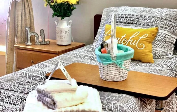 A cozy bedroom featuring a decorative basket and fresh flowers on the nightstand.