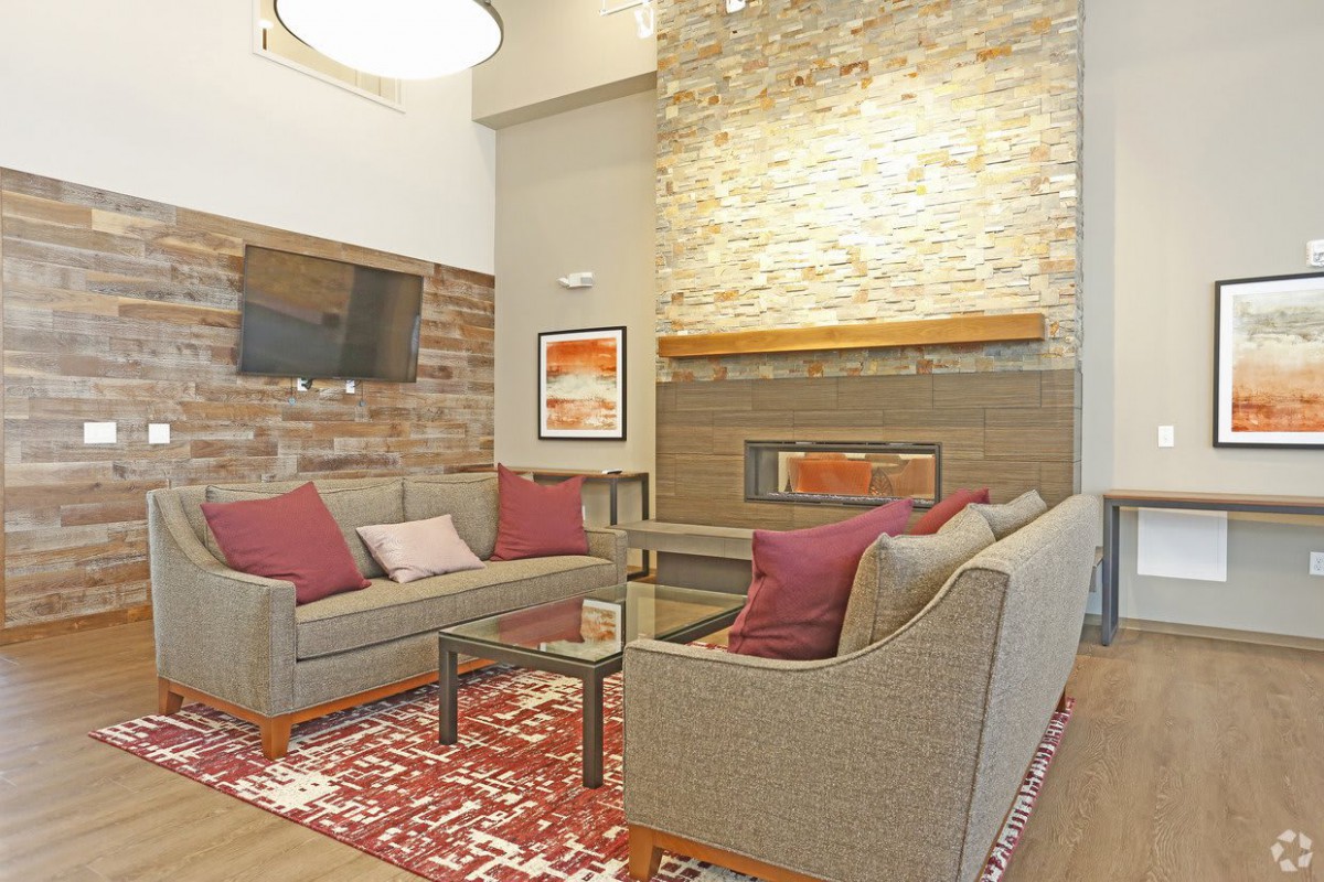A modern living room with cozy seating, a stone fireplace, and elegant decor.