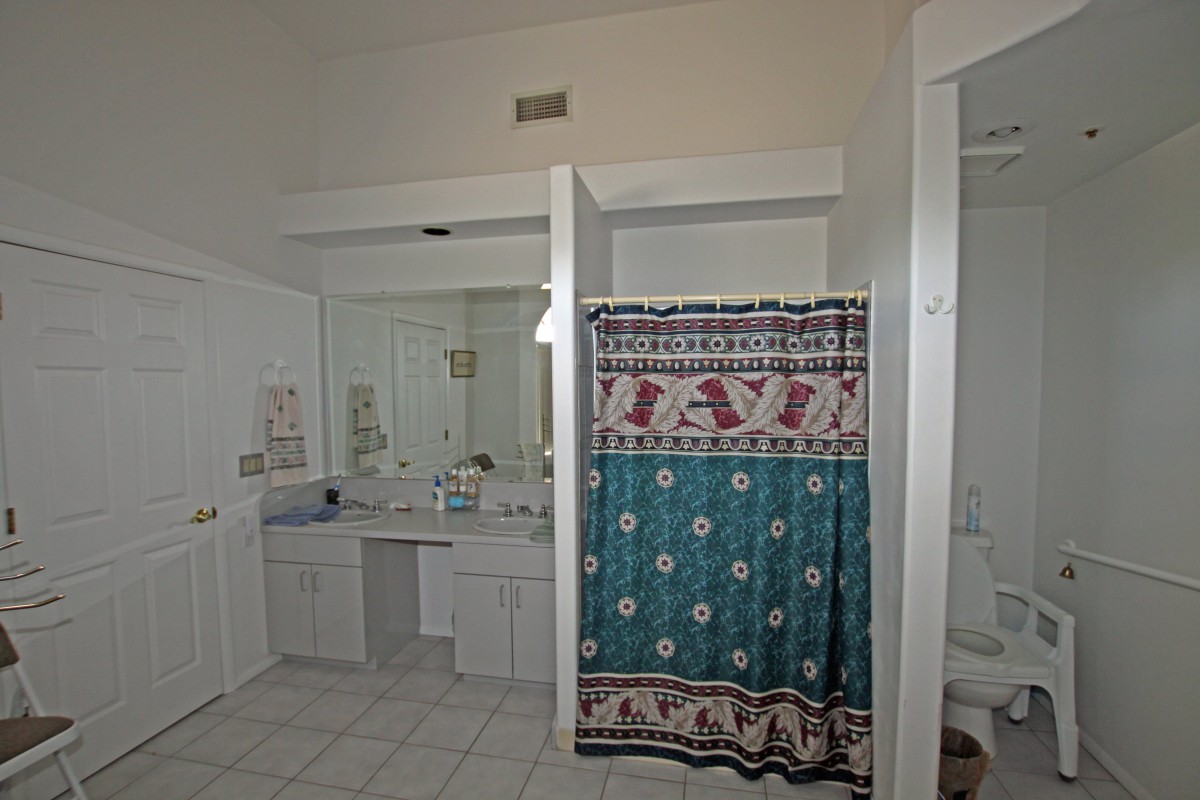 A spacious bathroom with a large mirror, sink area, and a decorative shower curtain.
