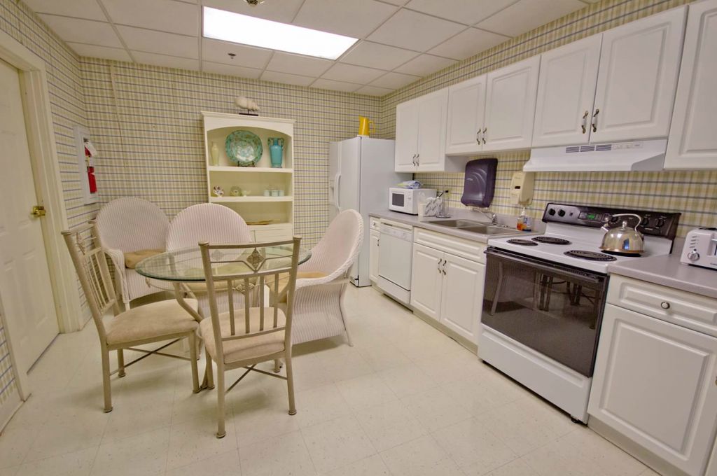 A modern kitchen with white cabinets, a dining table, and various appliances.