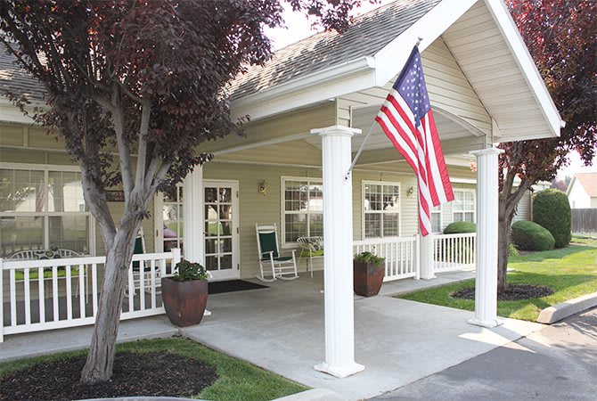 A house with a covered porch featuring an American flag and outdoor seating.