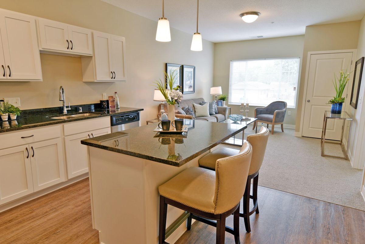 A modern open-concept kitchen with an island and dining area, featuring pendant lighting and counter stools.