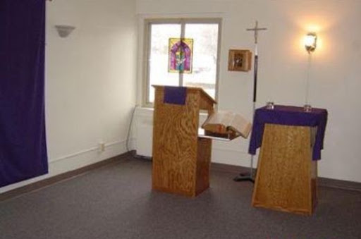 A serene interior view of a chapel with a wooden pulpit and altar, adorned with purple cloth.