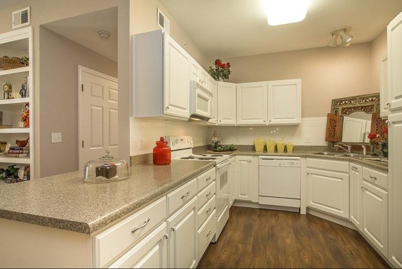 A modern kitchen with white cabinets and hardwood flooring.
