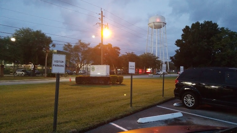 Evening scene of a parking lot with street lights and a distant water tower.