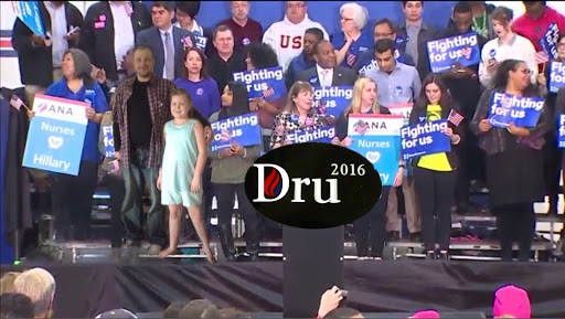 A diverse group of supporters at a political rally holding signs and expressing their support.