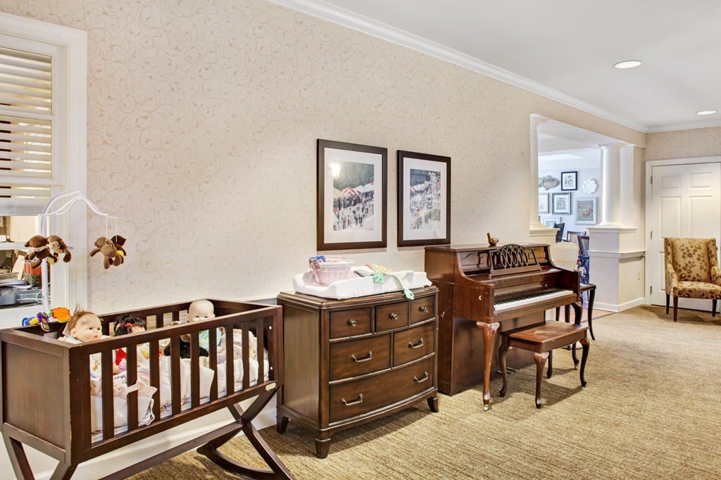 A cozy nursery with a crib, dresser, and piano setup.