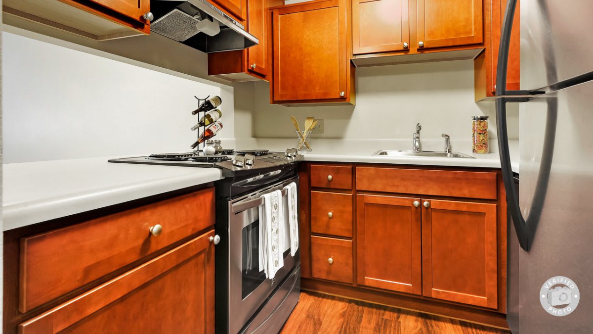 A cozy kitchen with wooden cabinets featuring a stove, oven, and sink.