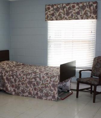A simple room with a bed, chair, and window.