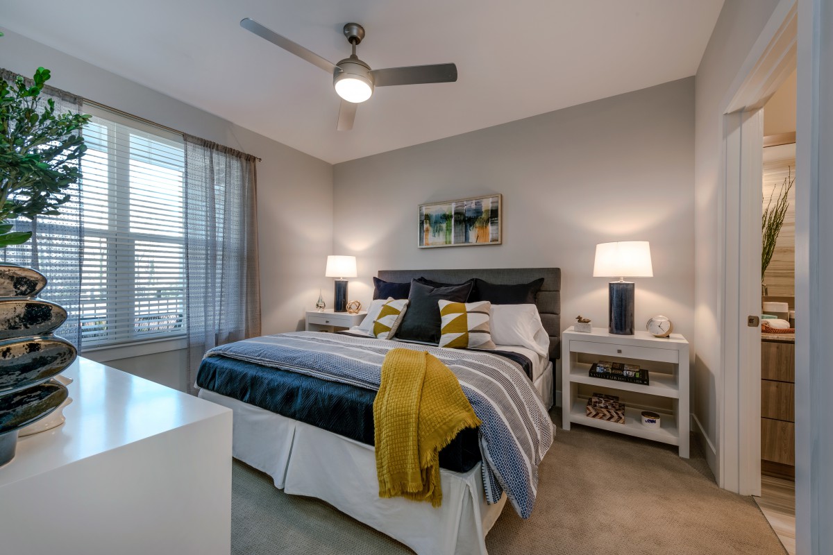 A modern bedroom with a double bed, stylish bedding, two lamps on nightstands, and artwork above the headboard.