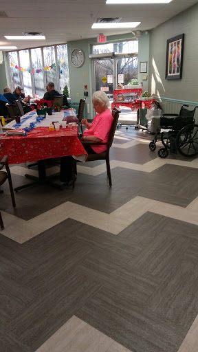 A cozy indoor space at a care facility, featuring tables with festive decorations and seating for residents.