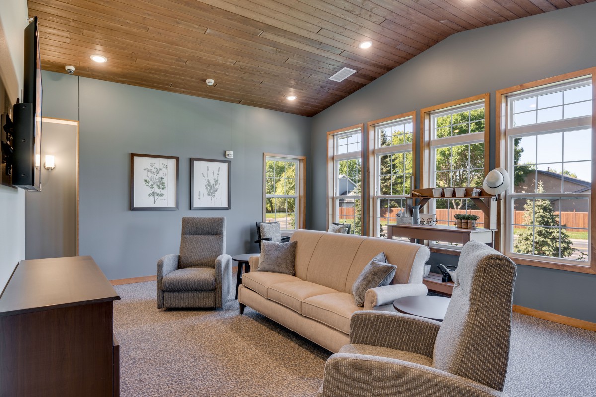 A cozy living room featuring a sofa, armchairs, and large windows allowing natural light to brighten the space.