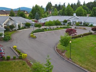 A scenic view of a residential facility surrounded by greenery and a curved driveway.