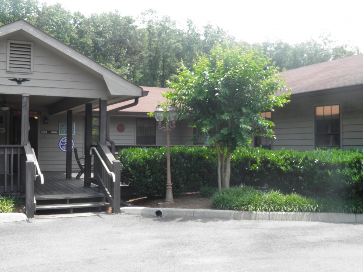 A small building surrounded by greenery with stairs leading up to the entrance.