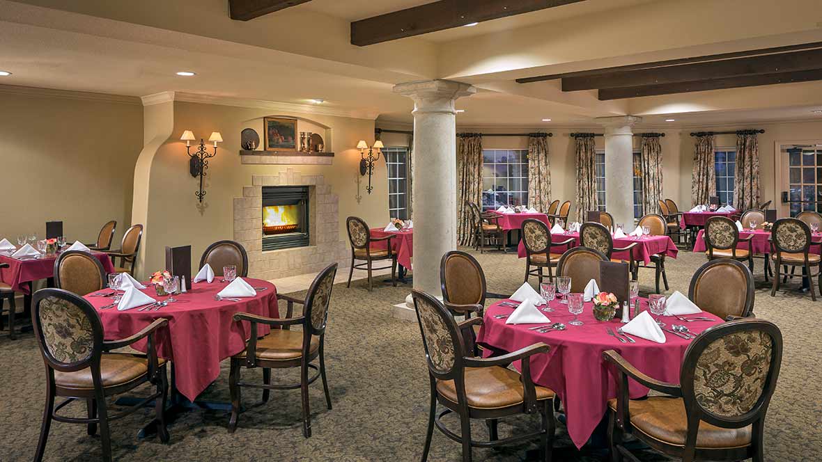 An elegant dining room with neatly set tables and a cozy fireplace.