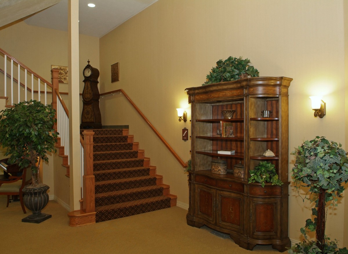 A traditional interior featuring a wooden bookshelf and staircase adorned with plants.