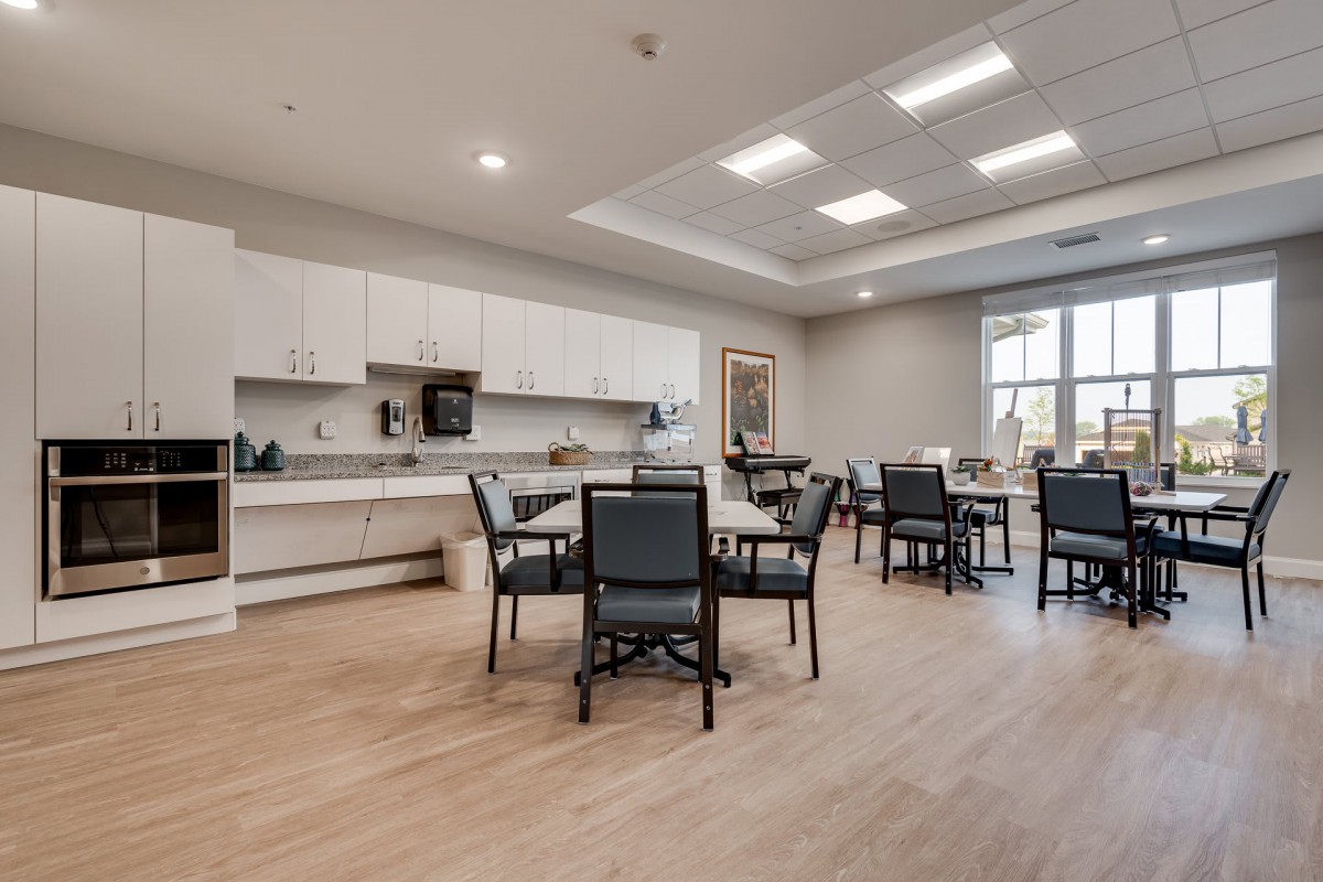 A modern kitchen and dining area with tables and chairs, featuring bright lighting and a spacious layout.