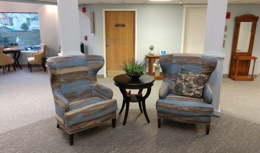 A cozy waiting area with two striped armchairs and a small round table.