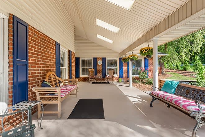 A cozy porch with comfortable seating, skylights, and decorative plants.